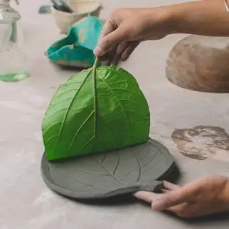 imprinting fig leaf on clay to make aura pottery signature fig leaf tray